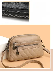 Close-up of quilted pattern and multi-zipper compartments on a beige crossbody bag