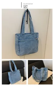 Detail view of light blue denim tote bag with functional side pockets and front zipper pocket