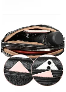 Detailed interior of black leather crossbody bag showing three zipper compartments and storage