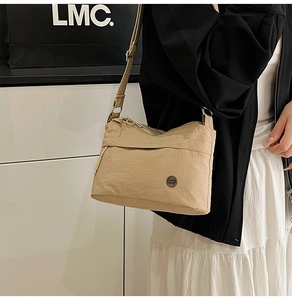 Detailed side view of beige nylon crossbody bag with adjustable strap and metal logo