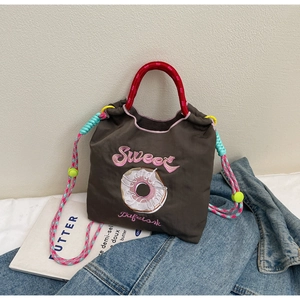 Détail du sac seau marron avec broderie sweet, poignée rouge et bandoulière