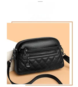 Detailed view of black lychee leather crossbody bag with rhombus quilting and double zippers