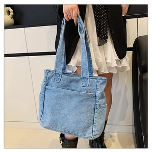 Detail of light blue denim tote bag showing side pockets and reinforced shoulder strap