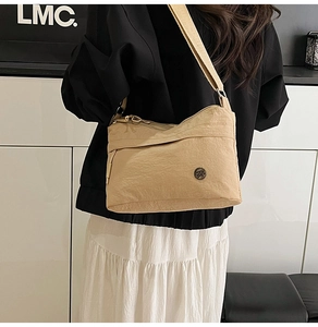 Rear view of a model wearing an apricot nylon crossbody bag with multi-zipper pockets