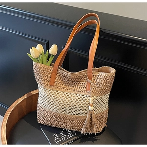 Detail der gewebten Stroh-Tote-Bag mit Streifenmuster, Ledergriffen und Quastenanhänger