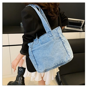 Macro view showing the spacious side pockets of the light blue denim tote bag on model