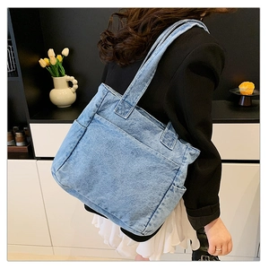 Detail of blue denim tote bag with side pockets shown in a casual lifestyle setting