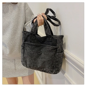 Close-up of black washed denim tote bag showing vintage texture and large front pocket