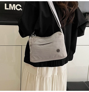 Detail of light grey waterproof nylon crossbody bag with adjustable wide fabric strap