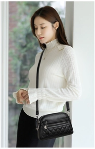 Close-up of black quilted leather shoulder bag featuring double zippers and silver hardware