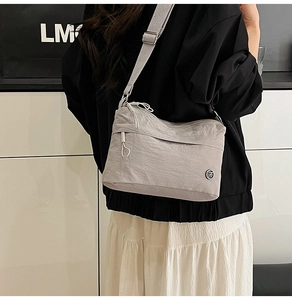 Detailed view of light gray water-resistant nylon crossbody bag with adjustable strap