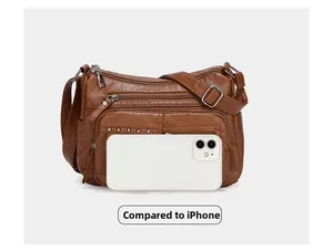 Détail du sac à bandoulière marron multi-zips avec un iPhone pour comparer la taille