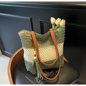 Detail der grün-beige gestreiften Strohtasche mit braunen Ledergriffen und Quasten