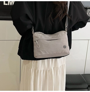 Detail of grey waterproof nylon crossbody bag showing zip pockets and shoulder strap fit