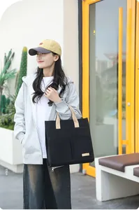 Detail of minimalist black canvas tote bag featuring two large front pockets and brown straps