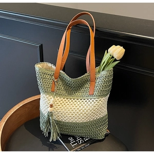 Detail der gewebten Stroh-Tote-Bag mit grünen Streifen und Lederriemen mit Quasten