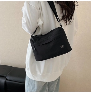 Close-up of a black nylon crossbody bag worn by a model in casual sportswear style