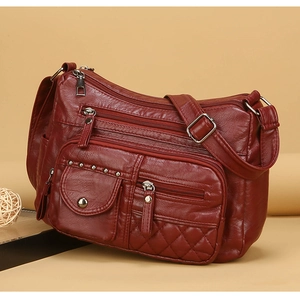 Détail du sac bandoulière bordeaux montrant les poches zippées et la texture matelassée