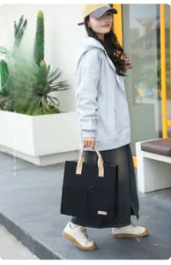 Close-up of black canvas tote bag showing contrast khaki handles and multiple exterior pockets