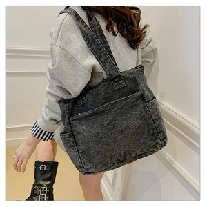 Detail view of large denim tote bag showing side pockets and washed fabric texture