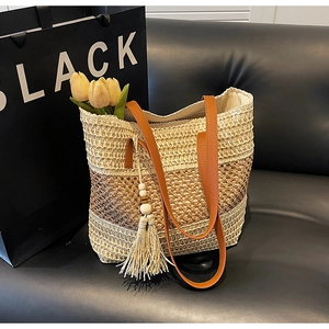 Detail der gewebten Strohtasche mit dreifarbigem Farbverlauf und braunen Ledergriffen