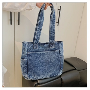 Detail of acid wash denim tote bag with front pocket and durable double handles