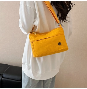 Detail view of water-resistant bright yellow crossbody bag with dual zipper compartments