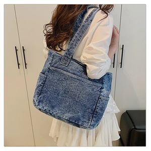 Close-up of a vintage blue denim tote bag with front pocket and washed texture