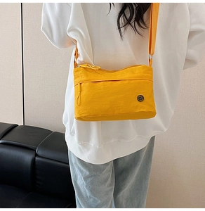 Detail of yellow nylon crossbody bag with adjustable strap and durable zip pocket