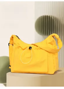 Detail of yellow canvas crossbody bag with drawstring pocket on display stand