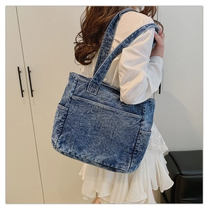Detail of dark blue denim tote bag with multiple pockets and snowflake wash texture
