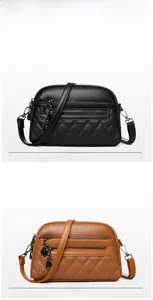 Detail showing litchi grain leather texture and metallic zipper pendant on shoulder bag