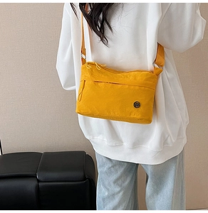 Model wearing a bright yellow nylon crossbody bag with adjustable shoulder strap