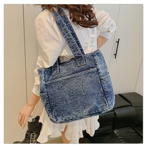 Detail of blue denim tote bag with side pockets shown on model for daily commuting