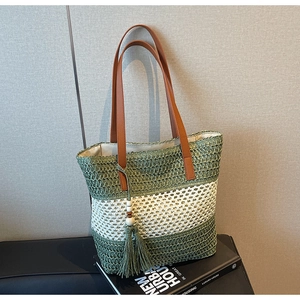 Detailansicht der gestreiften Stroh-Tote-Bag mit Ledergriffen und grünem Quastenanhänger