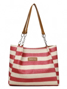 Detail of red and white striped straw tote bag featuring brown leather handles and logo