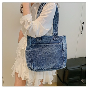 Detail of blue denim tote bag featuring large front pocket and functional side compartments