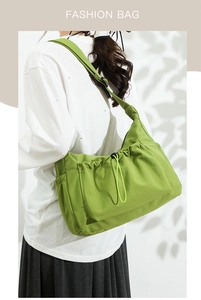 Detail of green nylon tote bag with drawstring pockets shown on a model