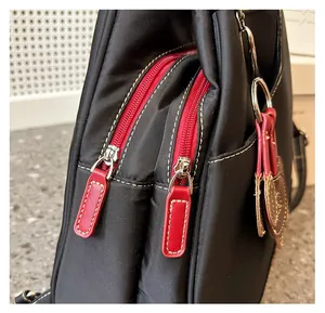 Detail of smooth red dual zippers and metallic hardware on a black nylon backpack