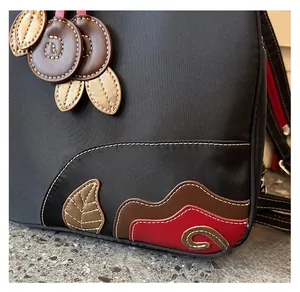 Detail of waterproof black nylon backpack featuring colorful leather floral applique