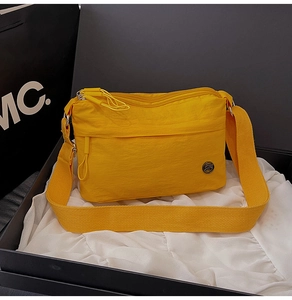 Detail view of water-resistant yellow nylon crossbody bag with wide strap in gift box