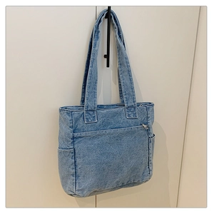Detailed macro view of light blue denim tote bag with large front pocket and side pockets