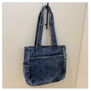 Detail of blue snowflake washed denim tote bag with functional pockets and sturdy straps
