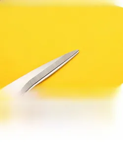 Detail of silver stainless steel scissors with golden rivet on yellow background