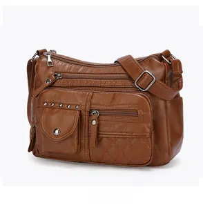 Détail du sac bandoulière en cuir marron foncé avec plusieurs poches et clous argentés
