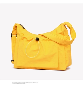 Detail of a bright yellow large canvas tote bag with adjustable strap and front pocket