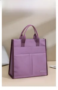 Detailed side view of purple canvas tote bag showing stitching and woven brand label