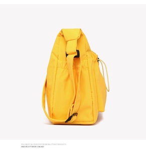 Detail of yellow canvas tote bag showing side elastic pocket and adjustable strap