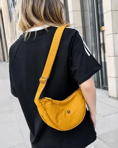 Dettaglio della borsa a mezzaluna in nylon giallo con tracolla e logo in metallo