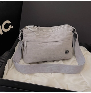 Detail of water-resistant nylon crossbody bag with multiple compartments and logo